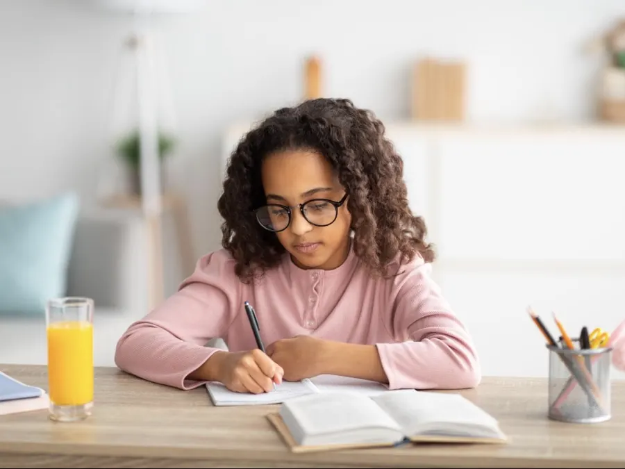 Une fille à lunettes faisant ses maths sur papier à la maison