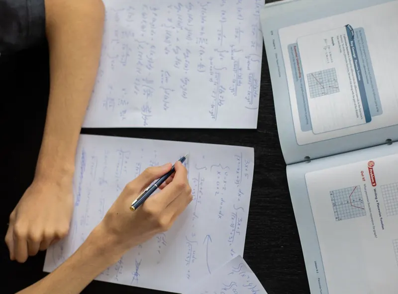Uma criança fazendo matemática no papel em uma mesa