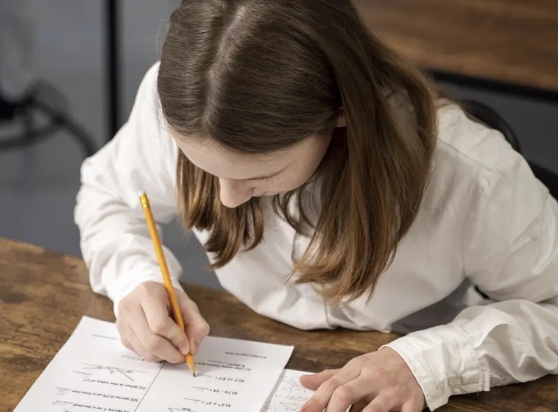 Un enfant qui fait des maths sur papier à un bureau
