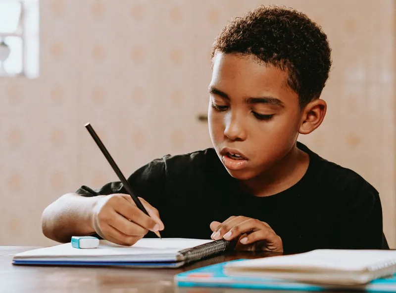 Un enfant qui fait des maths sur papier à un bureau