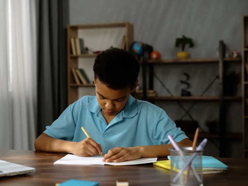 Un enfant qui fait des maths sur papier à un bureau