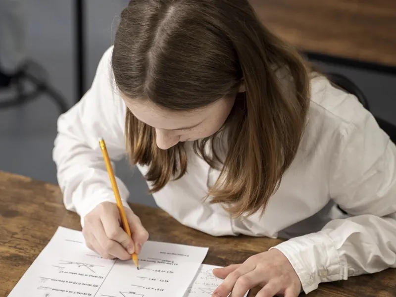 Uma criança fazendo matemática no papel em uma mesa